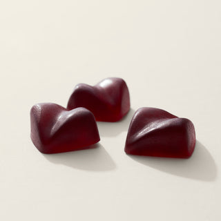 A photograph of three Camino Gummies in the Midnight Blueberry Flavor. They are a deep reddish color.