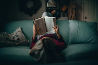 woman reading while high at home on couch
