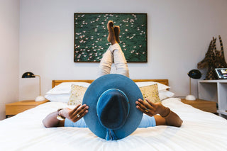 staycation ideas person laying on bed wearing hat